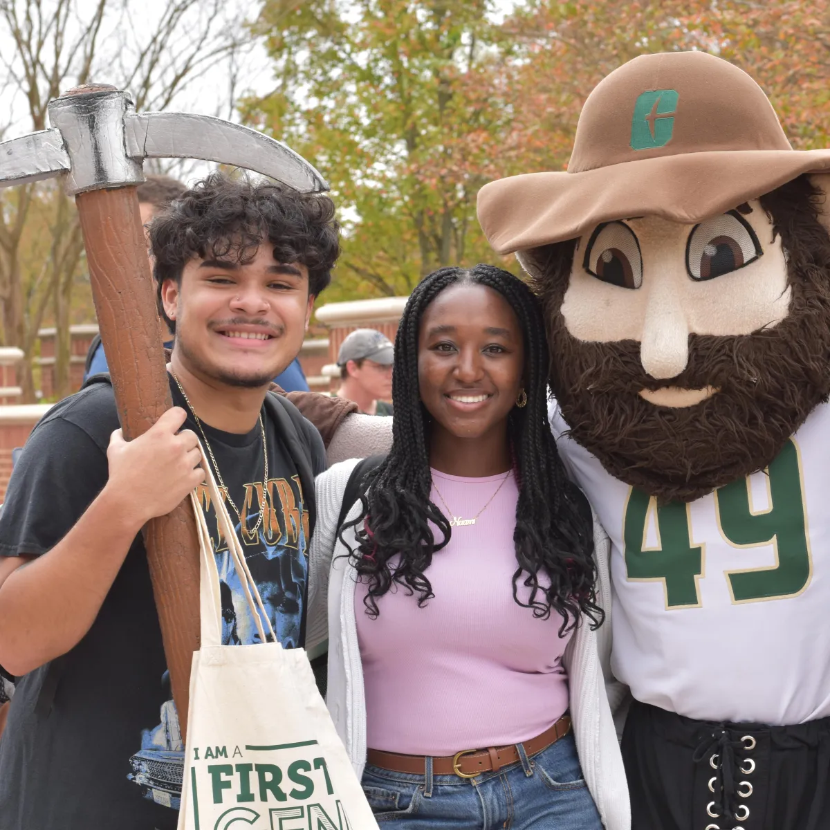 Three smiling first-gen students with Norm